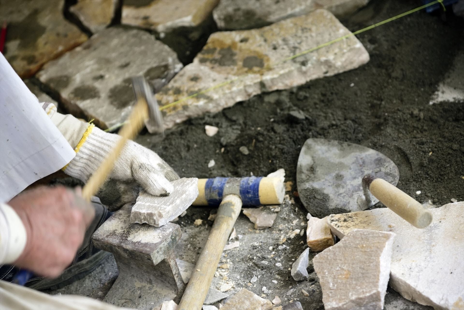 タイルをハンマーで叩くスタッフ